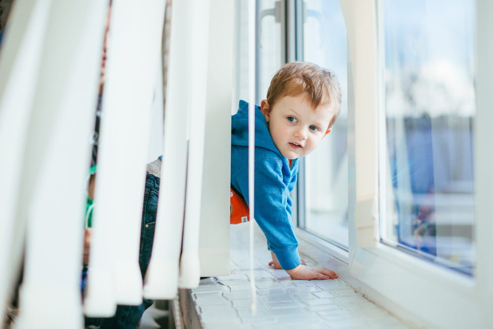 https://www.factorydirectblinds.com/cdn/shop/articles/small-boy-stands-near-window-sill_1000x.jpg?v=1699938564